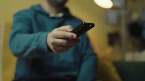 Close up of a hand clicking buttons on a TV remote control to change channels.	 Stock Footage 330361435