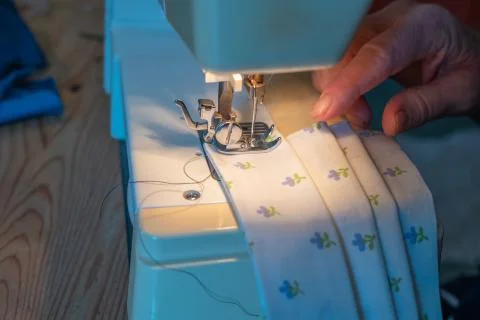A close up of a hand controlling the fabric and the needle of a sewing machine Stock Photos