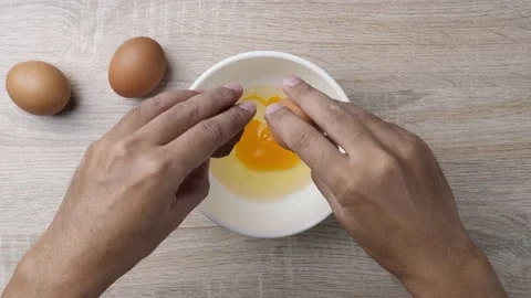 Close up hand cracked chicken egg in to a bowl for cooking scramble egg. Cooking Stockbeeldmateriaal 232942640