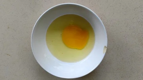 A close-up of a hand cracking an egg into a bowl Stock Footage 304058550