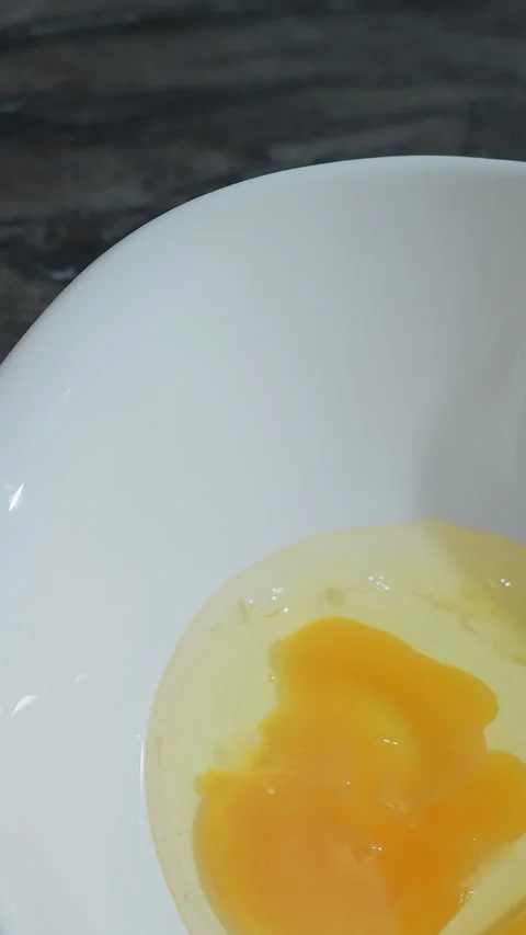 Close-Up of Hand Cracking Egg on Counter with Bowl Containing Broken Eggs Stock Footage 320338059