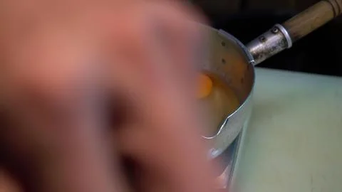 Close-up of hand cracking egg into metal bowl in kitchen 스톡 사진