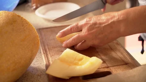 Close up of hand cut orange melon with knife on cutting board. HD Stock Footage 98884075