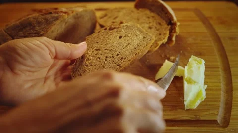 Close up of hand cut off piece of butter and spread on rye bread, top view of Stock Footage 279230587