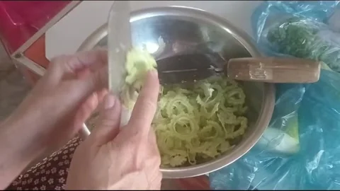 Close Up Hand Cutting Bitter Melon Into Thin Slices for Cooking Vídeos de archivo 335909997