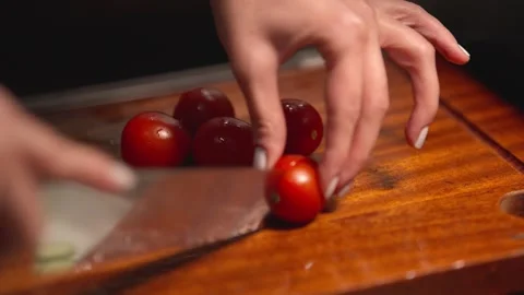 Close Up of Hand Cutting Cherry Tomatoes on Wooden Cutting Board Stock Footage 336466938