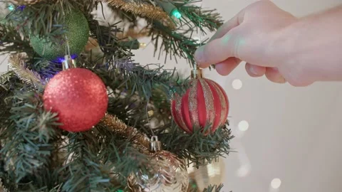 Close up of hand decorating christmas tree with ornaments 库存影片 220755438