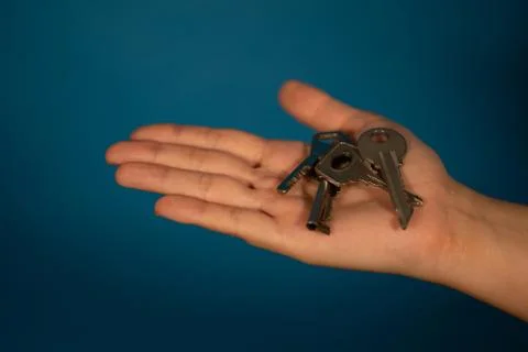 Close-up of hand with different keys. Huddle of keys on woman's palm on blue Foto stock