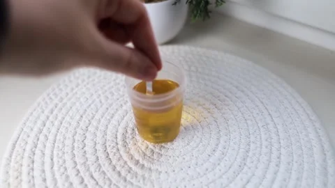 A close-up of a hand dipping a urine test strip into a container for medical dia Stock-Footage 344944549