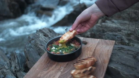 Close up of hand dips bread in yolk on background wild river at spring time Stock Footage 271552099