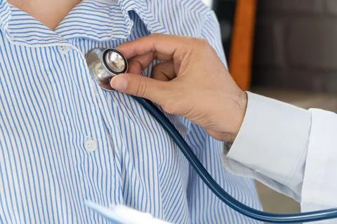 Close-up Hand doctor using stethoscope to exam woman patient heart. Doctor li Stock Photos