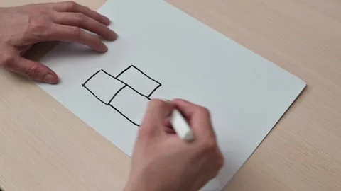A close-up of a hand drawing block shapes and the text "SYSTEM" on a sheet of Vidéo 337550248