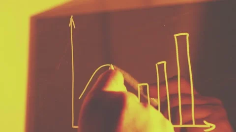 Close-up of hand drawing upward-trending bar and line graph in warm Stock Footage 321634695