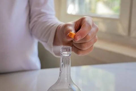 Close-Up Hand Dropping Orange Crystal into Flask Horizontal Foto stock
