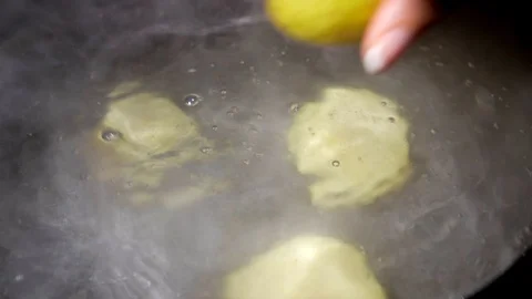Close up hand dropping potatoes in boiling water Stock Footage 125496999