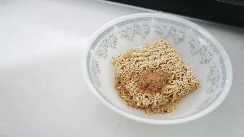 Close up of Hand dumping MAMA instant noodle seasoning powder onto the noodle Stock Footage 107914188
