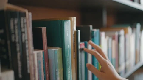 Close-up of hand female pulling book from bookshelf in public library Stock Footage 211417827