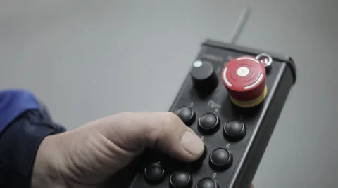 Close-up of a hand fingering a button on an industrial remote control in a logis Stock Footage 36840792