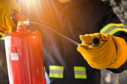 Close up hand Fireman using fire extinguisher fighting. Stock Photos