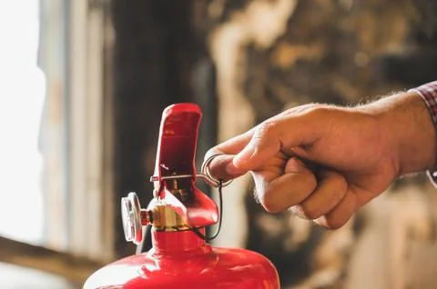 Close up hand Fireman using fire extinguisher fighting. Hand pulling pin of.. Stock Photos