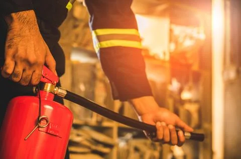 Close up hand Fireman using fire extinguisher fighting. Stock Photos