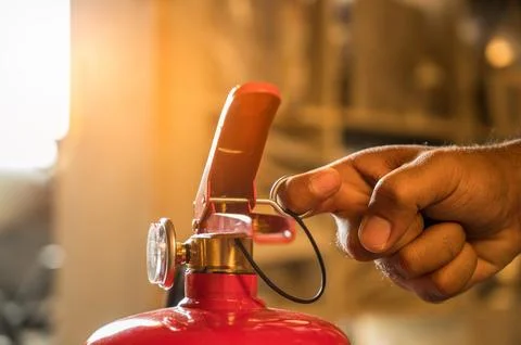 Close up hand Fireman using fire extinguisher fighting. Hand pulling pin of.. Stock Photos