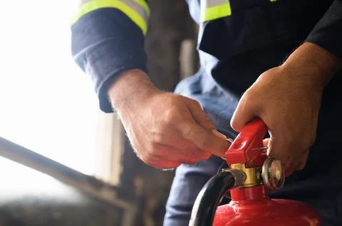 Close up hand Fireman using fire extinguisher fighting. Hand pulling pin of.. Stock Photos