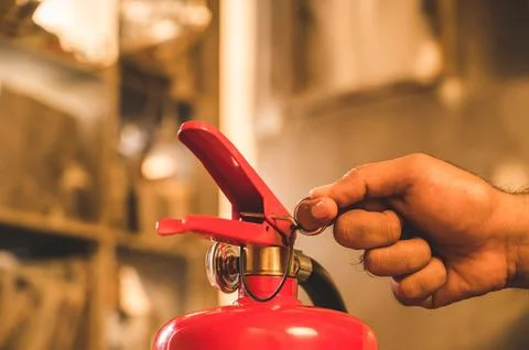 Close up hand Fireman using fire extinguisher fighting. Hand pulling pin of.. Stock Photos