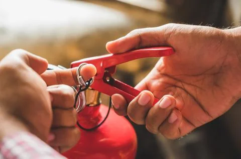 Close up hand Fireman using fire extinguisher fighting. Hand pulling pin of.. Stock Photos