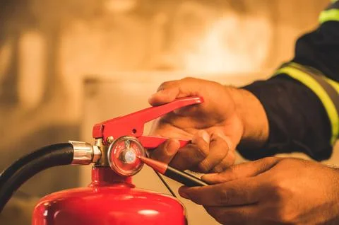 Close up hand Fireman,Firefighter checking the fire extinguisher. Stock Photos
