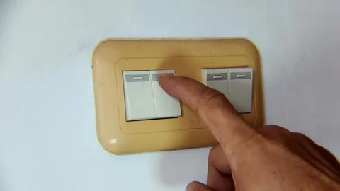 Close-up of hand flipping wall light switch to turn on light Stock Footage 338447992