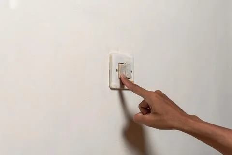 Close-up hand flips a wall light switch on and off Stock Photos