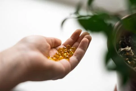 Close up of hand full of yellow softballs. Taking supplements, vitamin D or Stock Photos