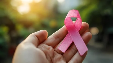 Close-up of a hand gently holding a pink awareness ribbon, symbolizing hope Video stock 314649809