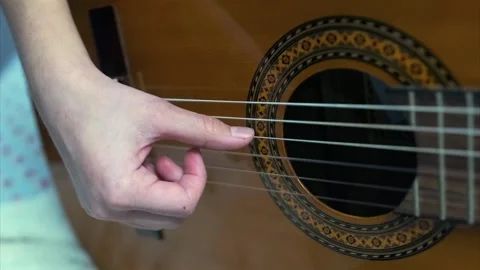 Close-up of a hand gently plucking guitar strings on a classical acoustic guitar Stock Footage 314495486