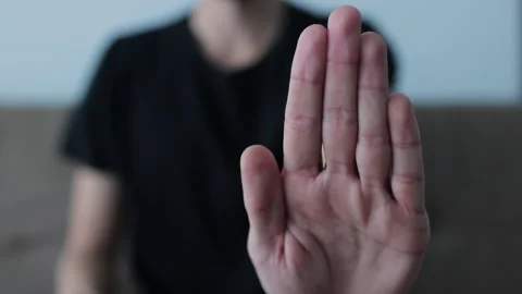 Close-up of a hand gesturing to stop, with a blurred figure in the background Stock Footage 327158410