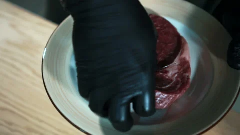 Close-up hand in gloves takes piece of raw meat and puts it on table. Stock Footage 87322382