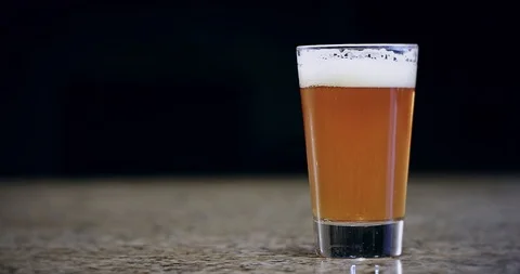Close up of a hand grabbing a pint of beer and sliding it on a bar 4k Stock Footage 104458690