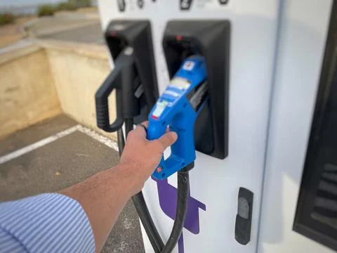Close-up of a hand grasping the plug of an electric car charging station Stock Photos