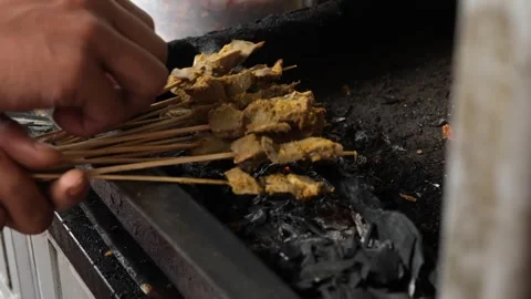 Close-up of Hand Grilling Authentic Indonesian Chicken Satay Skewers Over Hot Ch Stock Footage 337441099