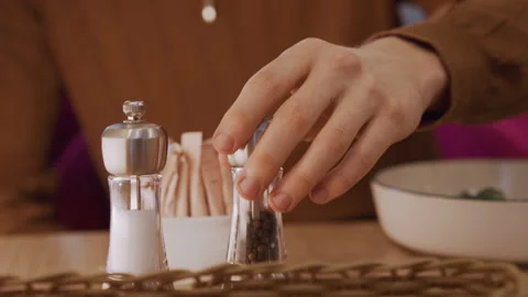 Close up of hand grinding pepper in salt and pepper shakers on table with sugar 動画素材 345732071