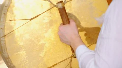 Close up of a hand gripping the handle of a large frame drum, with warm light Stock Photos