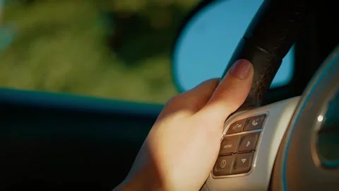 Close-up hand gripping steering wheel with mirror reflecting outdoors. Fingers Stock Footage 306317876