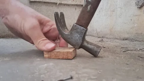 Close-up of a hand hammering a nail into concrete surface. Construction worker Stock Footage 340922453