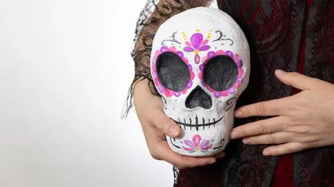 Close-up of a hand-held painted papier-mache sugar skull cradled with reveren Stock Photos