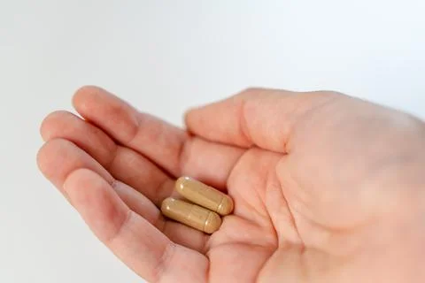 Close up hand with herb capsule on white background. Microdosing concept Stock Photos