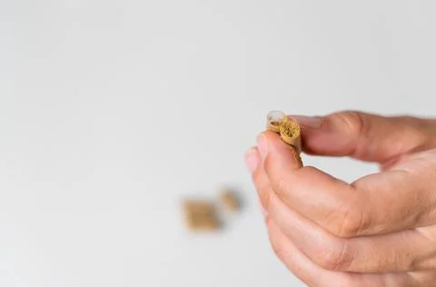 Close up hand with herb capsule on white background. Microdosing concept Stock Photos