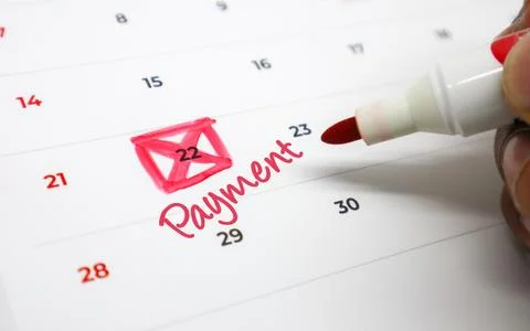 Close up of a hand highlighting an important payment due date on a calendar.. Stock Photos