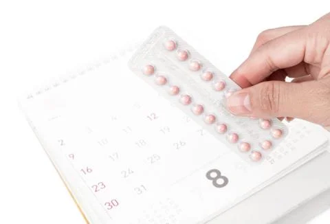 Close up hand hold birth-control pill with date of calendar background, healt Stock Photos