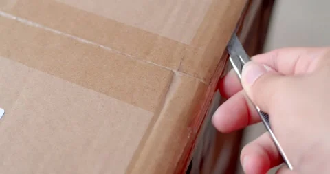 Close up hand hold Cutter Knife cut tape attached on the delivery box. Stock Footage 253105701